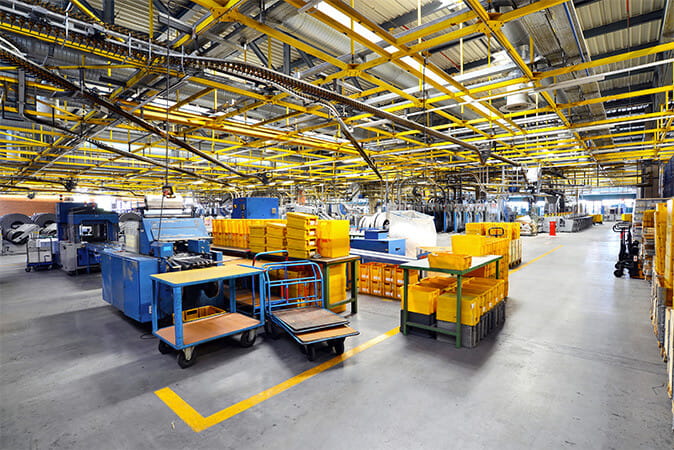 Clean manufacturing floor with organized equipment, worktables, and clearly marked yellow walkways