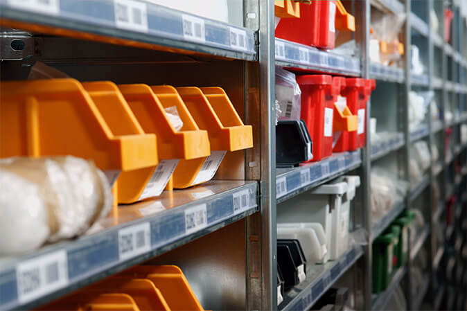 Rows of orange and gray storage bins arranged consistently on industrial shelving