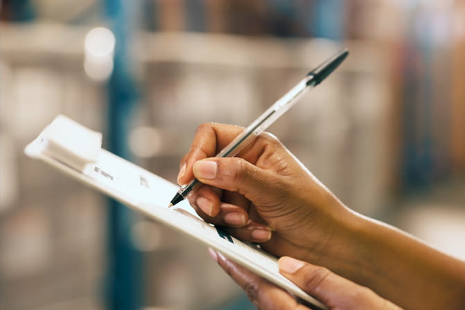 Employee writing on a clipboard while inspecting a workplace